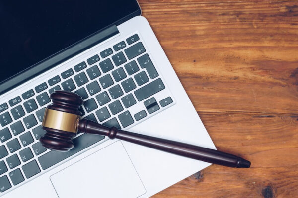 Auction gavel laying on a laptop on a wooden desk.
